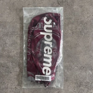 Supreme balaclava Money SS25, bordowa kominiarka z nadrukiem dolarów i dużym logo Supreme